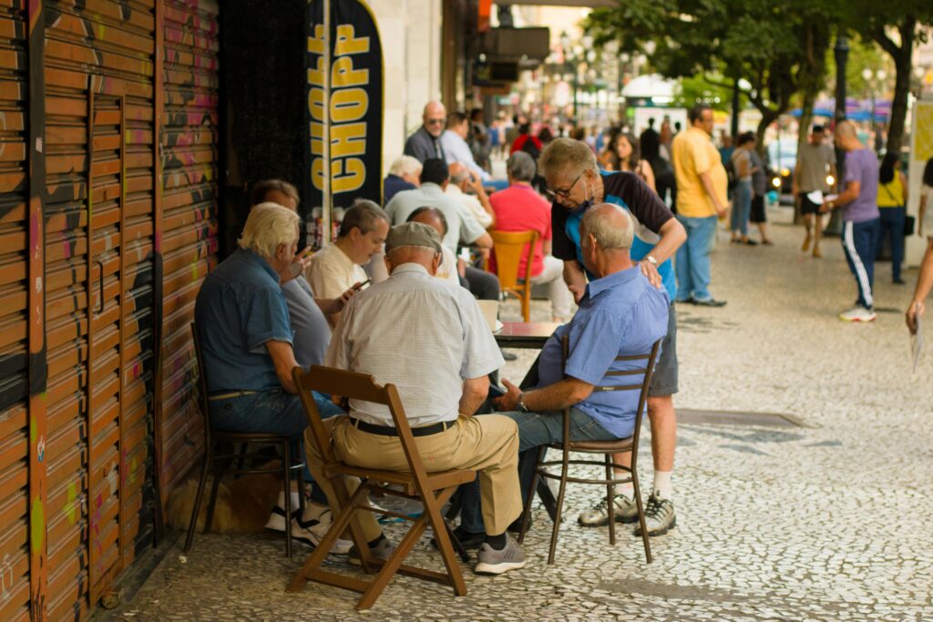 07 dicas para equilibrar a vida pessoal e a profissional Elderly men enjoy leisure time sitting together outdoors in an urban setting, promoting social connections.