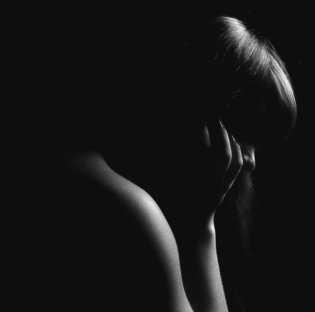 Dramatic black and white silhouette of a woman in deep thought.
