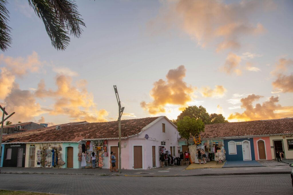 Colorful colonial-style houses at sunset in Porto Seguro, Brazil, with hanging decorations and vibrant sky.