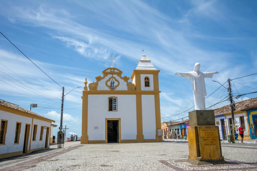 Historic church and Christ statue in Porto Seguro, showcasing colonial architecture.
